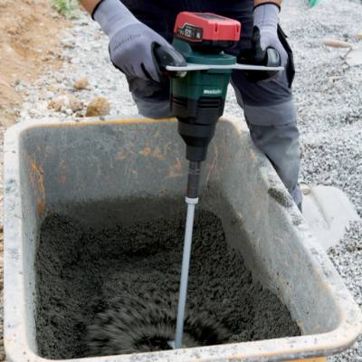Misturadora elétrica Metabo a misturar cimento numa cuba amarela num sitio de construção