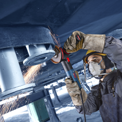 Homem a usar esmeril elétrico Bosch para lixar metal cinzento