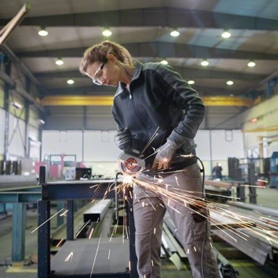 Pessoa a cortar metal com esmerilhadora elétrica num espaço industrial