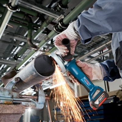 Máquina de corte elétrica azul a cortar tubo metálico com faíscas em ambiente industrial