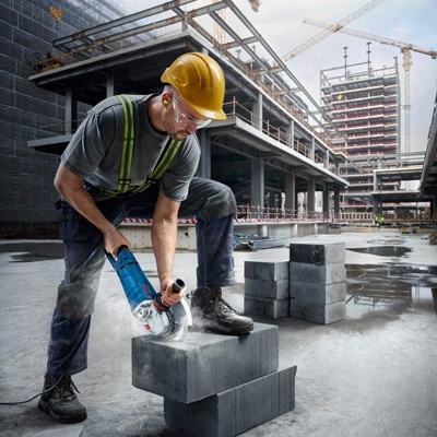Trabalhador da construção civil a cortar blocos de cimento com máquina num estaleiro de construção