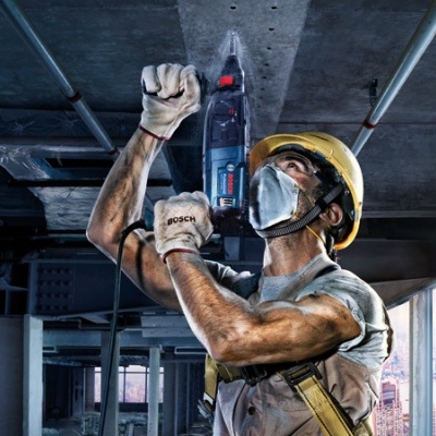 Operário de construção a usar ferramenta elétrica com vista da cidade