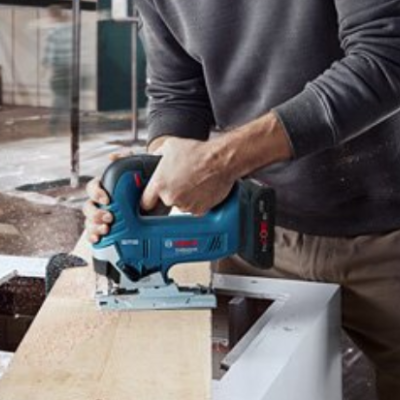 Serra tico-tico Bosch azul e preta a cortar madeira numa oficina