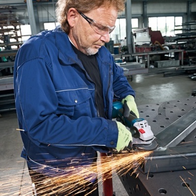 Homem a usar rebarbadora eléctrica para trabalhar metal numa oficina