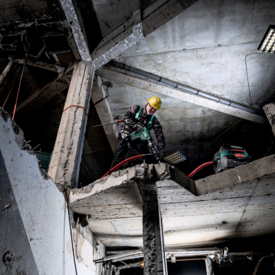 Trabalhador de construção com capacete amarelo em estrutura de betão deteriorada