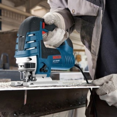 Serra tico-tico azul e preta Bosch a cortar chapa metálica com operador a usar luvas