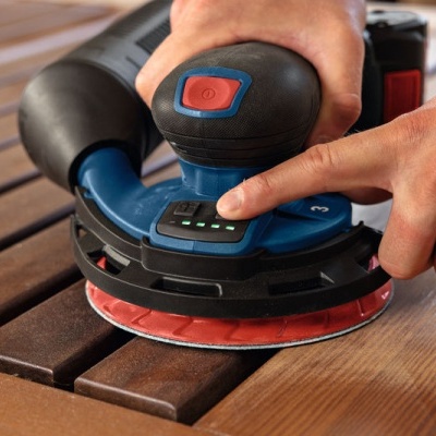 Lixadora elétrica azul e preta com base vermelha a ser usada em madeira