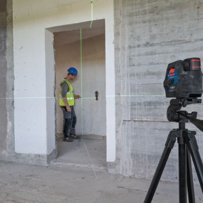 Laser nível num tripé numa obra com trabalhador ao fundo