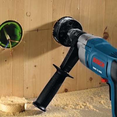 Broca Bosch GSB 13 RE a fazer orifício numa parede de madeira clara com fios elétricos