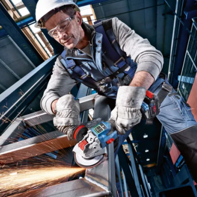 Homem a usar rebarbadora elétrica numa oficina industrial