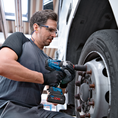 Homem a usar chave de impacto numa roda de camião