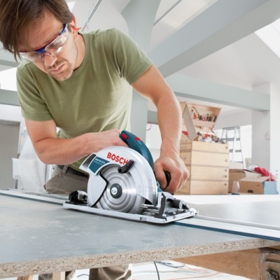Máquina de cortar circular BOSCH a ser usada por um homem com óculos de proteção numa bancada