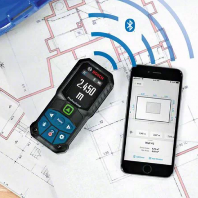 Medidor de distância Bosch GLM 50 C com smartphone e plantas arquitetónicas sobre mesa de madeira