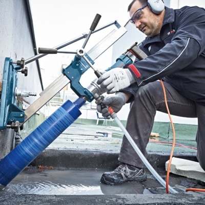 Homem a operar ferramenta de perfuração azul fixada à parede