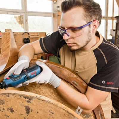 Homem a trabalhar numa peça de mobiliário de madeira com ferramenta elétrica BOSCH numa oficina