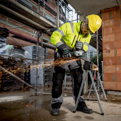 Trabalhador em construção a usar esmerilhadora elétrica com faiscamento.