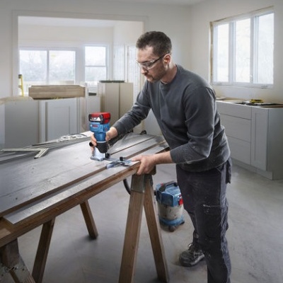 Homem a usar furadeira Bosch em bancada de madeira num espaço de construção