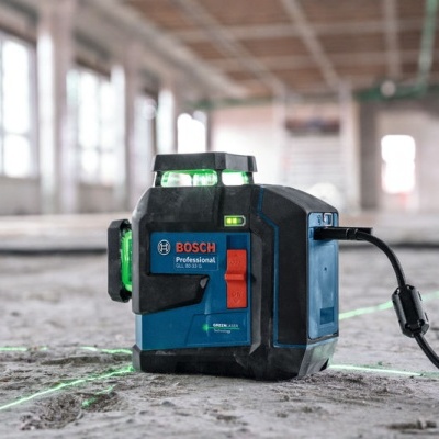 Laser de construção Bosch Professional azul e preto com linhas laser verdes no chão
