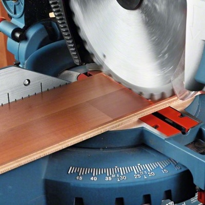Serra de esquadria elétrica azul a cortar madeira clara.
