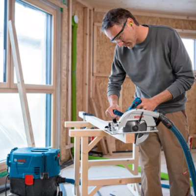 Homem a cortar madeira com serra circular Bosch em ambiente de construção