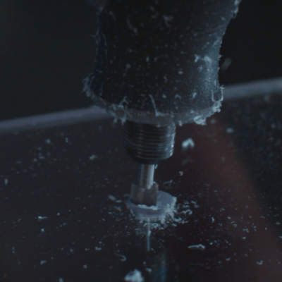 Máquina elétrica preta cortando acrílico transparente com resíduos brancos