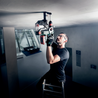 Homem a usar ferramenta elétrica no teto em ambiente interior moderno