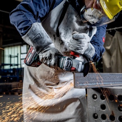 Trabalhador a usar rebarbadora para cortar metal numa oficina