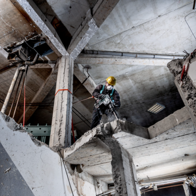 Trabalhador de capacete demole estrutura de cimento numa construção