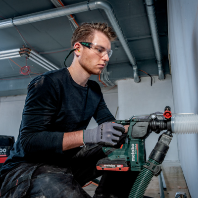 Homem a usar ferramenta elétrica Metabo com tubo branco em parede interior