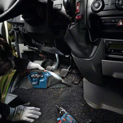 Interior de viatura com homem a aspirar tapete junto aos pedais