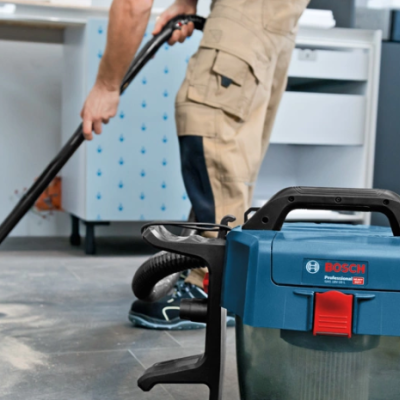 Aspirador portátil Bosch Professional azul e cinza com pessoa a aspirar o chão
