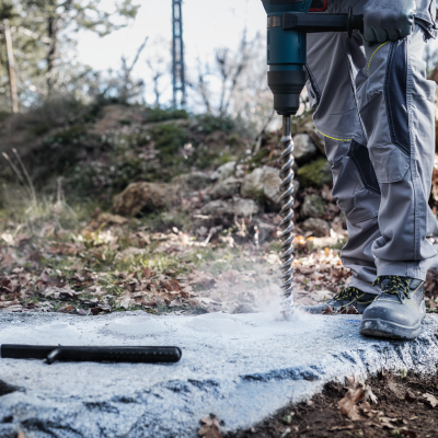 Trabalhador a perfurar uma pedra com berbequim elétrico ao ar livre