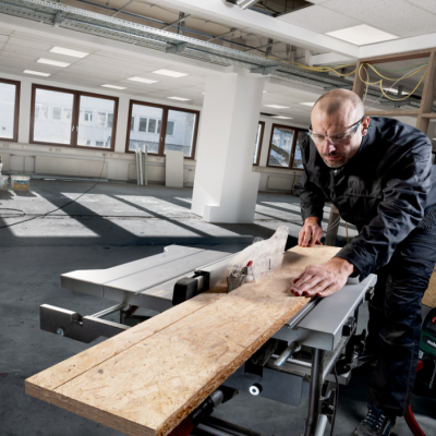 Homem a cortar madeira OSB com máquina de corte em espaço industrial