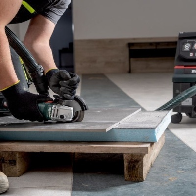 Trabalhador a usar lixadeira elétrica Metabo com aspirador no interior