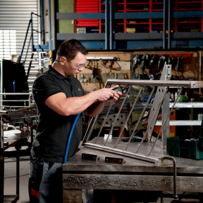 Homem a trabalhar numa peça metálica numa oficina com caixa de ferramentas verde Eagleeye.
