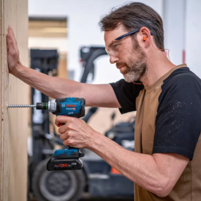 Homem a usar parafusador elétrico Bosch para fixar madeira