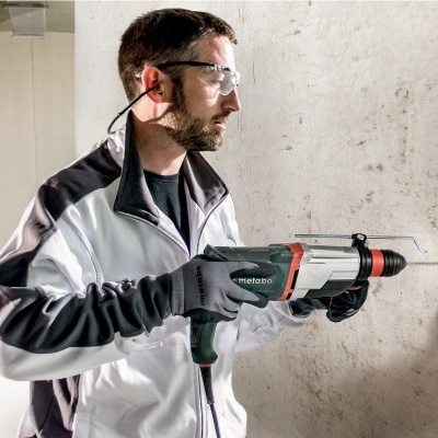 Homem usando pistola de calafetagem Metabo numa parede branca interior