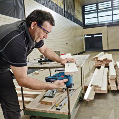 Homem a trabalhar com ferramenta elétrica em madeira numa oficina ampla