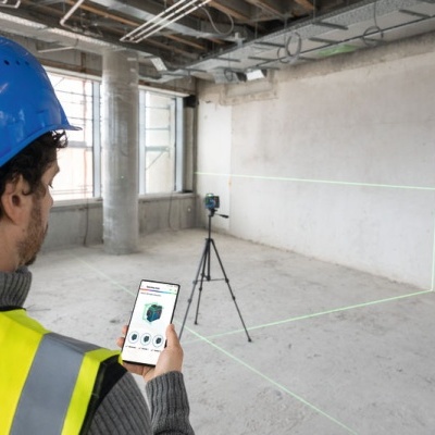Trabalhador com equipamento de medição laser numa sala de construção vazia
