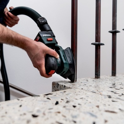 Ferramenta elétrica Bosch a trabalhar em pedra clara com mãos visíveis