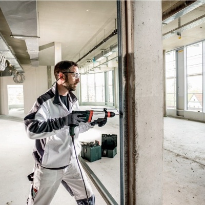 Homem a usar furadeira elétrica em construção