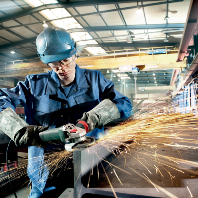 Homem a usar esmeril angular metálico produzindo faíscas num ambiente industrial