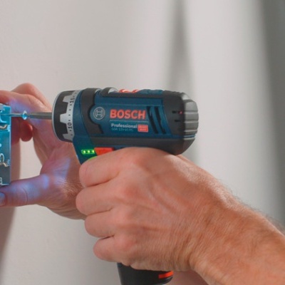 Pessoa a usar ferramenta Bosch Professional azul e preto para montar componente elétrico na parede