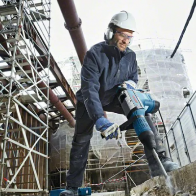 Trabalhador da construção a usar martelo demolidor num canteiro de obras