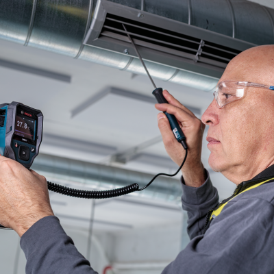 Homem a medir temperatura de ar condicionado com termómetro digital