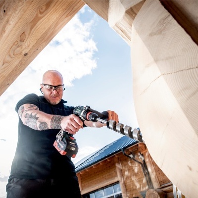 Homem com furadeira a trabalhar em madeira ao ar livre