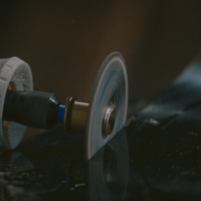 ferramenta rotativa com disco a trabalhar em superfície preta brilhante