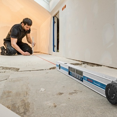 Homem mede distância no chão inacabado com ferramenta laser Bosch