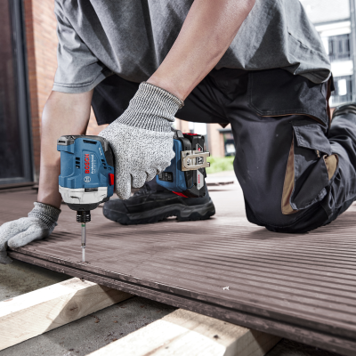 Parafusadeira Bosch Professional a aparafusar tábua de madeira castanho no exterior.