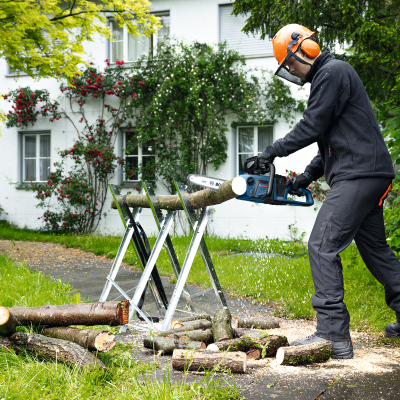 Homem a cortar troncos com motosserra Bosch no jardim